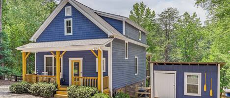 A two-story house with a porch, a small shed, and a gravel driveway.
