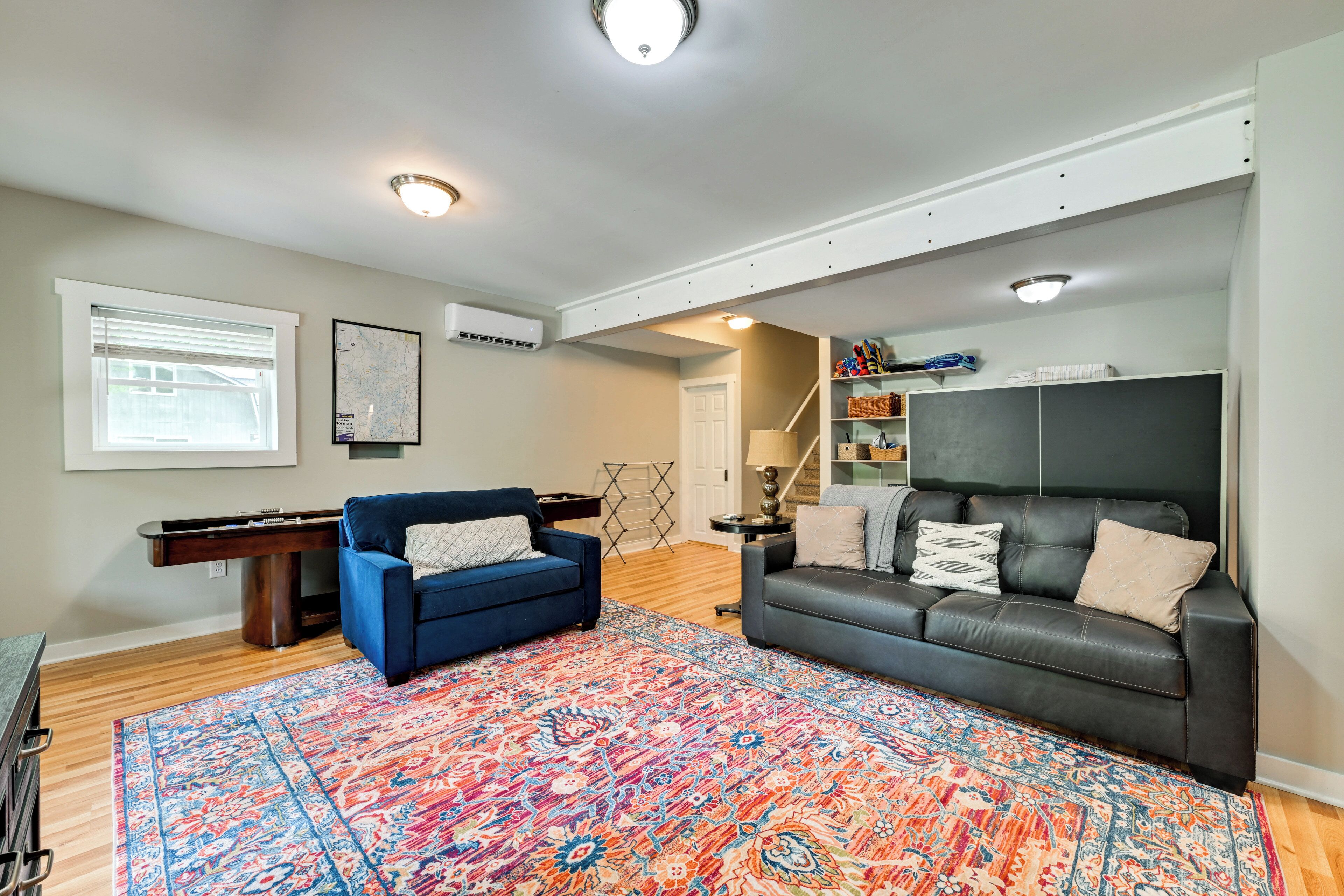Ein Wohnzimmer mit blauem Sofa, schwarzem Sofa, Teppich mit Muster, Billardtisch und einer Karte an der Wand.