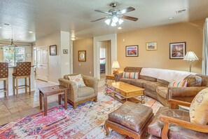 A living room with a ceiling fan, a patterned rug, a sofa, a coffee table, and a dining area with chairs. - Near Zion! Extended Desert Retreat w/ Pool Access (Washington)