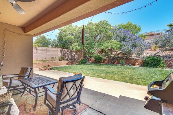 An outdoor patio with a table and chairs, a barbecue grill, and a view of a landscaped garden with trees and shrubs. - Near Zion! Extended Desert Retreat w/ Pool Access (Washington)