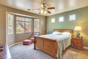 A bedroom with a bed, a nightstand, a lamp, a ceiling fan, and large windows. - Near Zion! Extended Desert Retreat w/ Pool Access (Washington)