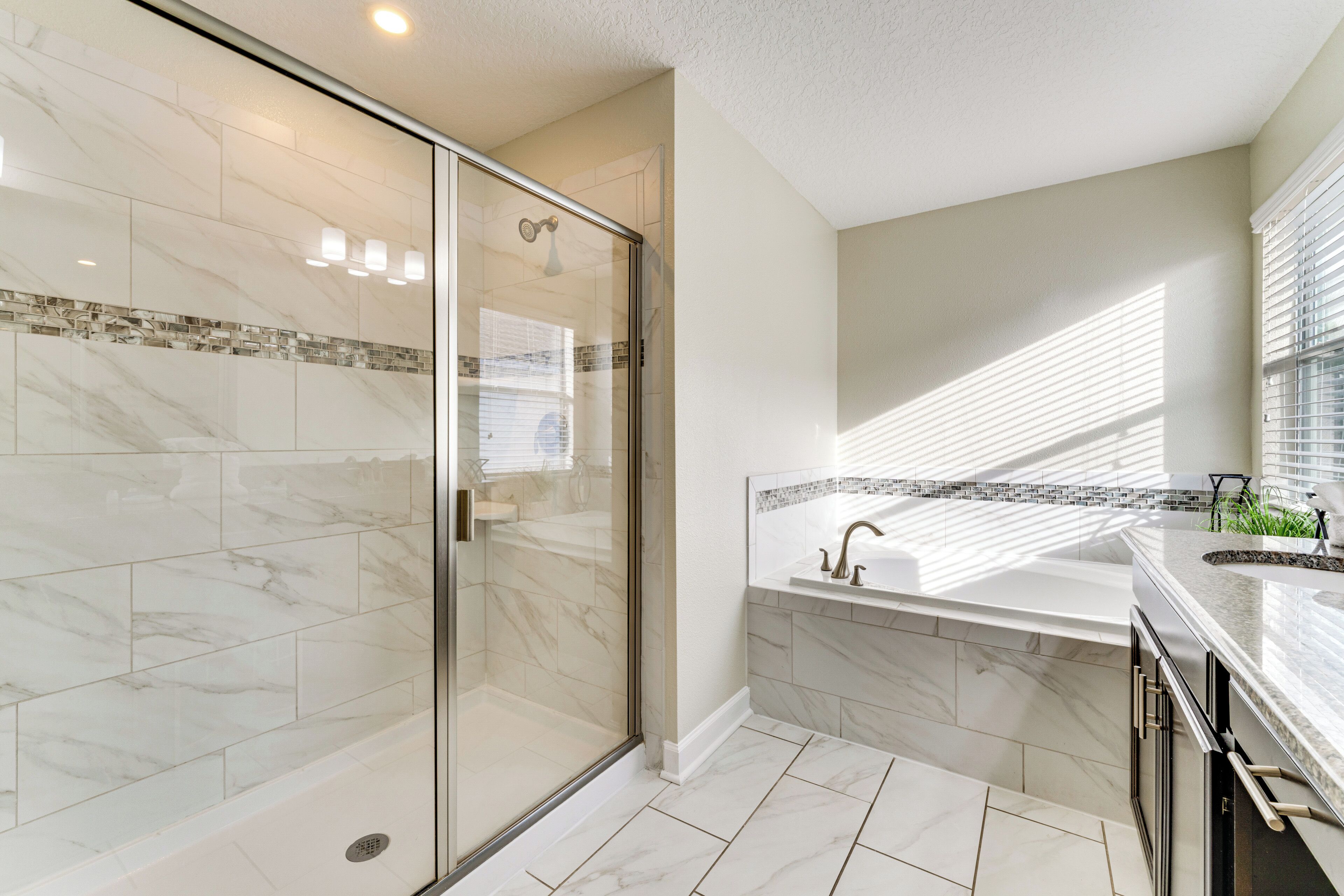 A modern bathroom with a glass-enclosed shower, a large bathtub, and a vanity with a sink.