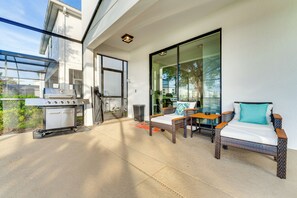 A patio with a grill, a wicker sofa, and a glass door leading to a balcony. - Disney! Universal! Free On-site Resort For All! (Kissimmee)