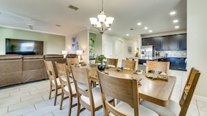 A dining area with a round table, wooden chairs, and a chandelier. - Disney! Universal! Free On-site Resort For All! (Kissimmee)
