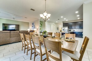 A dining area with a round table, wooden chairs, and a chandelier. - Disney! Universal! Free On-site Resort For All! (Kissimmee)