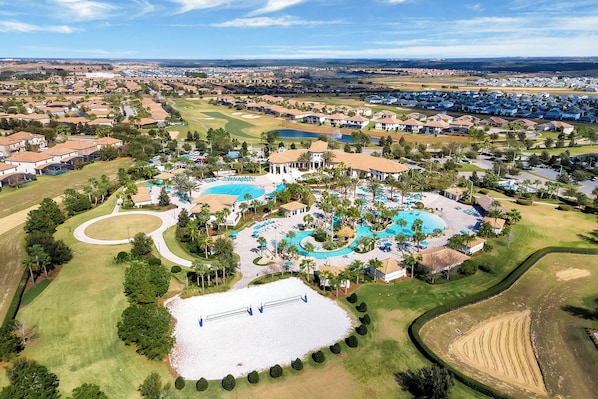 Eine Vogelperspektive zeigt eine Wohngegend mit mehreren Schwimmbädern, Golfplätzen und einem großen Wasserkörper.