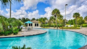 A swimming pool with a curved edge, surrounded by palm trees and a gazebo. - Game Room, Theater & More! Home 11 Mi to Disney (Davenport)