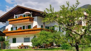 A multi-story building with balconies, a dining area, and a garden. - Apartment 'Haus Bernhard  A' with Mountain View, Balcony and Wi-Fi (Verdins)