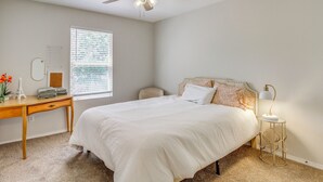 Un dormitorio con cama, escritorio, silla, lámpara de pie y ventilador de techo.