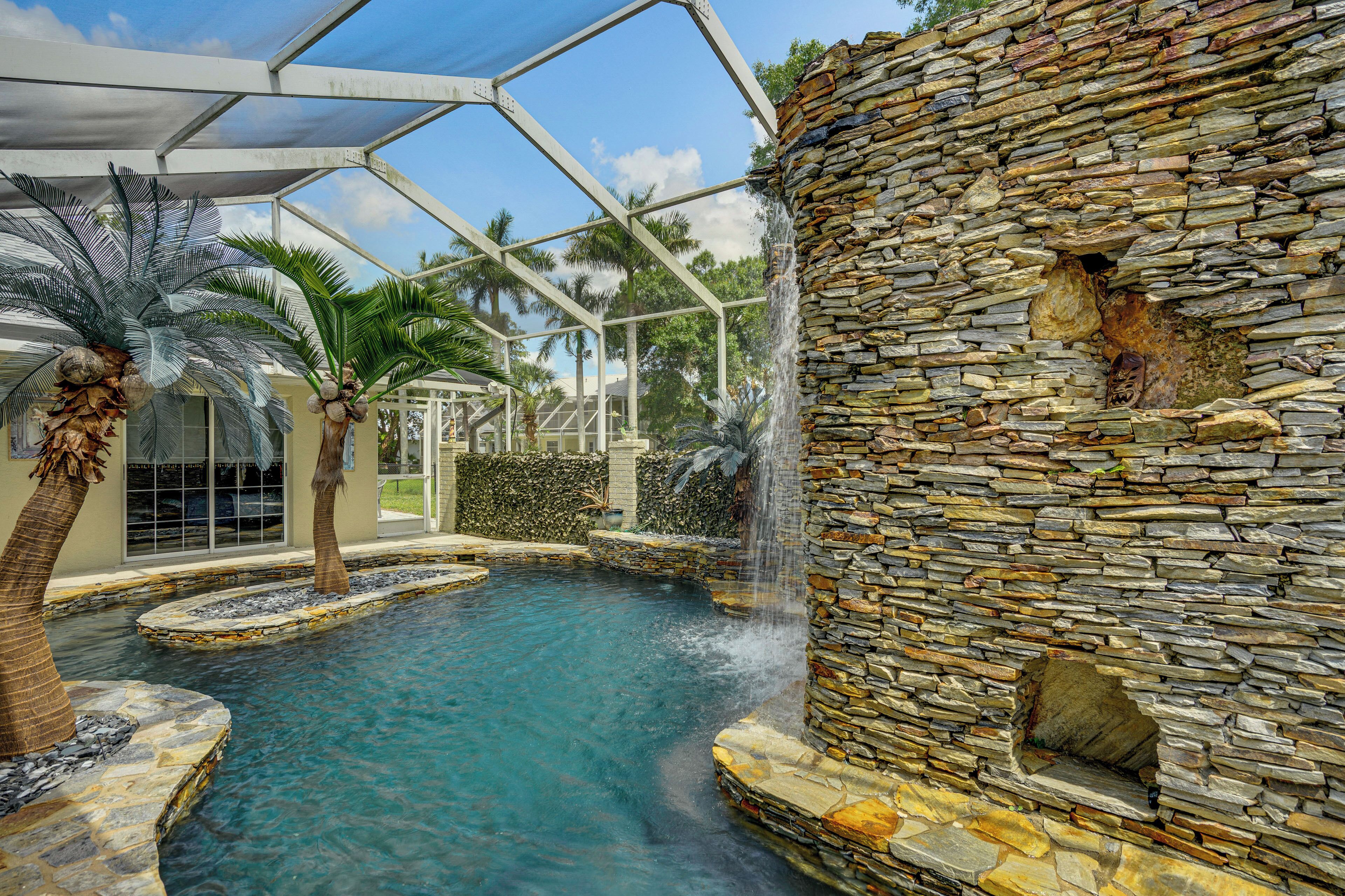 Una piscina interior con cascada, rodeada de muros de piedra y palmeras.
