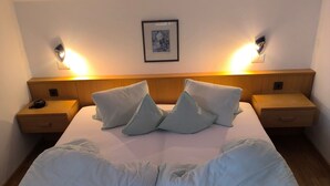 Un letto con una testiera in legno, due comodini, un quadro appeso alla parete e una lampada da comodino.