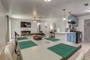 Eine moderne Küche mit Essbereich, Deckenventilator und Wandfernseher.