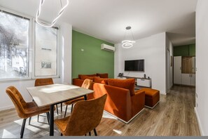 Ein modernes Interieur mit Essbereich, Sofagarnitur und an der Wand montiertem Fernseher.