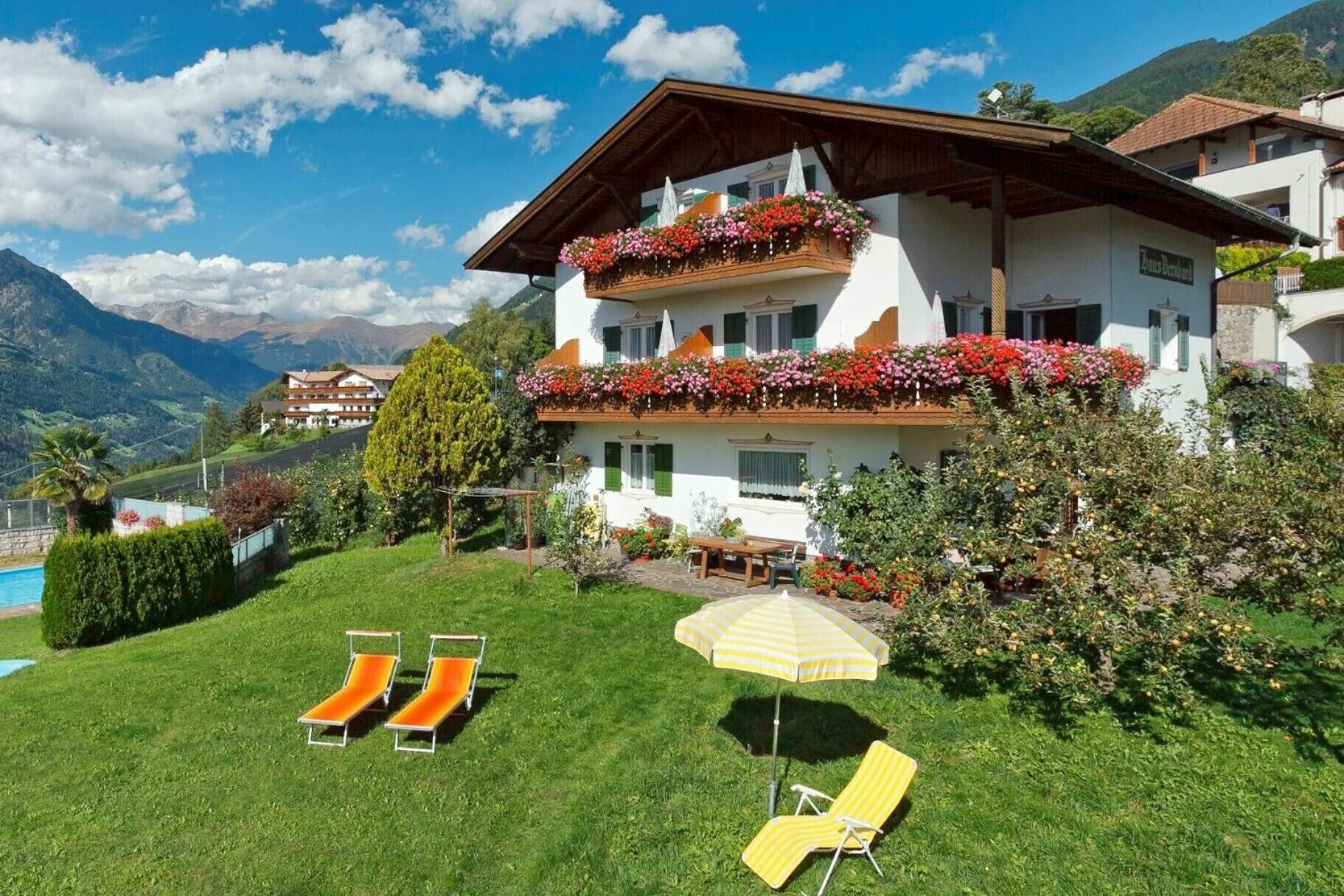 A two-story building with balconies, a pool, and a grassy lawn with lounge chairs.