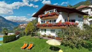 Un bâtiment à deux étages doté de balcons, d’une piscine et d’une pelouse verdoyante avec des chaises longues.