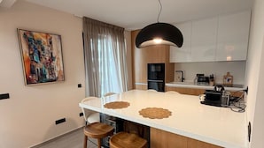 Una cocina moderna con una isla central, taburetes de madera, una lámpara colgante y un cuadro en la pared.