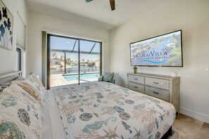 A bedroom with a large bed, a sliding glass door to a pool, and a view of the ocean. - Villa Happy Place - on water, pool, spa, views, boating (Cape Coral)