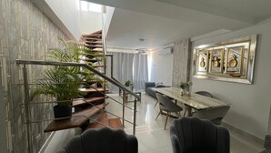 A modern interior with a staircase, dining area, and a wall with framed artwork. - Penthouse 2BR w/ Private Rooftop Terrace + Views (Santo Domingo)