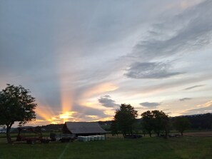 Paisagem rural com um celeiro, árvores e um trator.