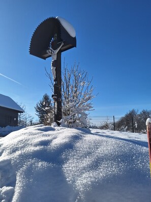 Paisagem coberta de neve com uma estrutura metálica, uma árvore e uma cerca.