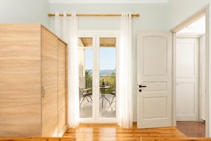 Ein Zimmer mit Holzschrank, einer Schiebeglastür, die zu einer Außenpatio mit Tisch und Stühlen führt, und einer weißen Tür.