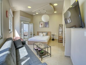 A modern bedroom with a bed, a sofa, a glass coffee table, a small side table, and a wardrobe. - Easy Stay - A Fresh Getaway in Kefalos Kos (Kos)