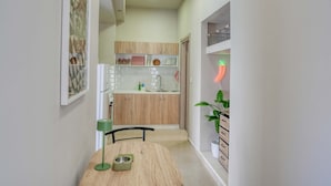 A narrow hallway leading to a kitchen with wooden cabinets, a white countertop, and a neon chili sign. - Easy Stay - A Fresh Getaway in Kefalos Kos (Kos)