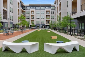 A courtyard with outdoor seating, a central lawn, and multi-story residential buildings. - Sapphire Sunset Modern Retreat Near Lake Pool Gym (Rowlett)
