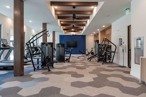A gym with exercise equipment, a treadmill, and a television on the wall. - Sapphire Sunset Modern Retreat Near Lake Pool Gym (Rowlett)
