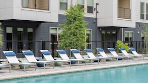 Un espace aménagé au bord de la piscine, avec des chaises longues et un arbre.