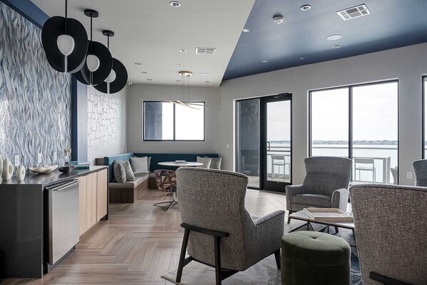 A modern interior with a kitchen, seating area, and large windows offering a view. - Sapphire Sunset Modern Retreat Near Lake Pool Gym (Rowlett)