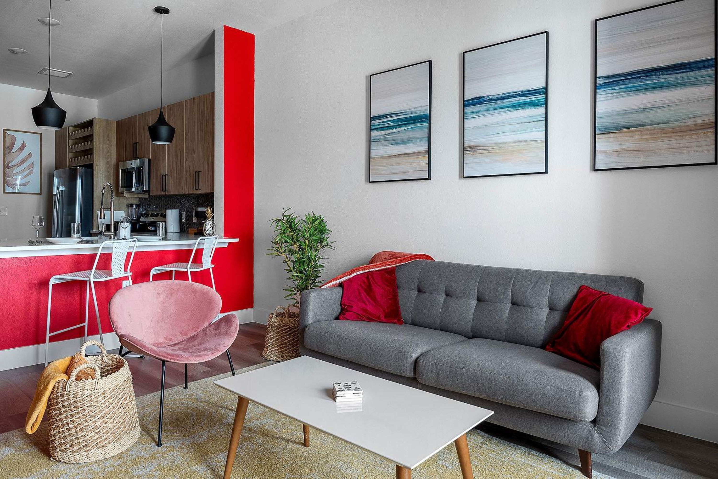 A modern living room with a grey sofa, a white coffee table, and a red accent wall.