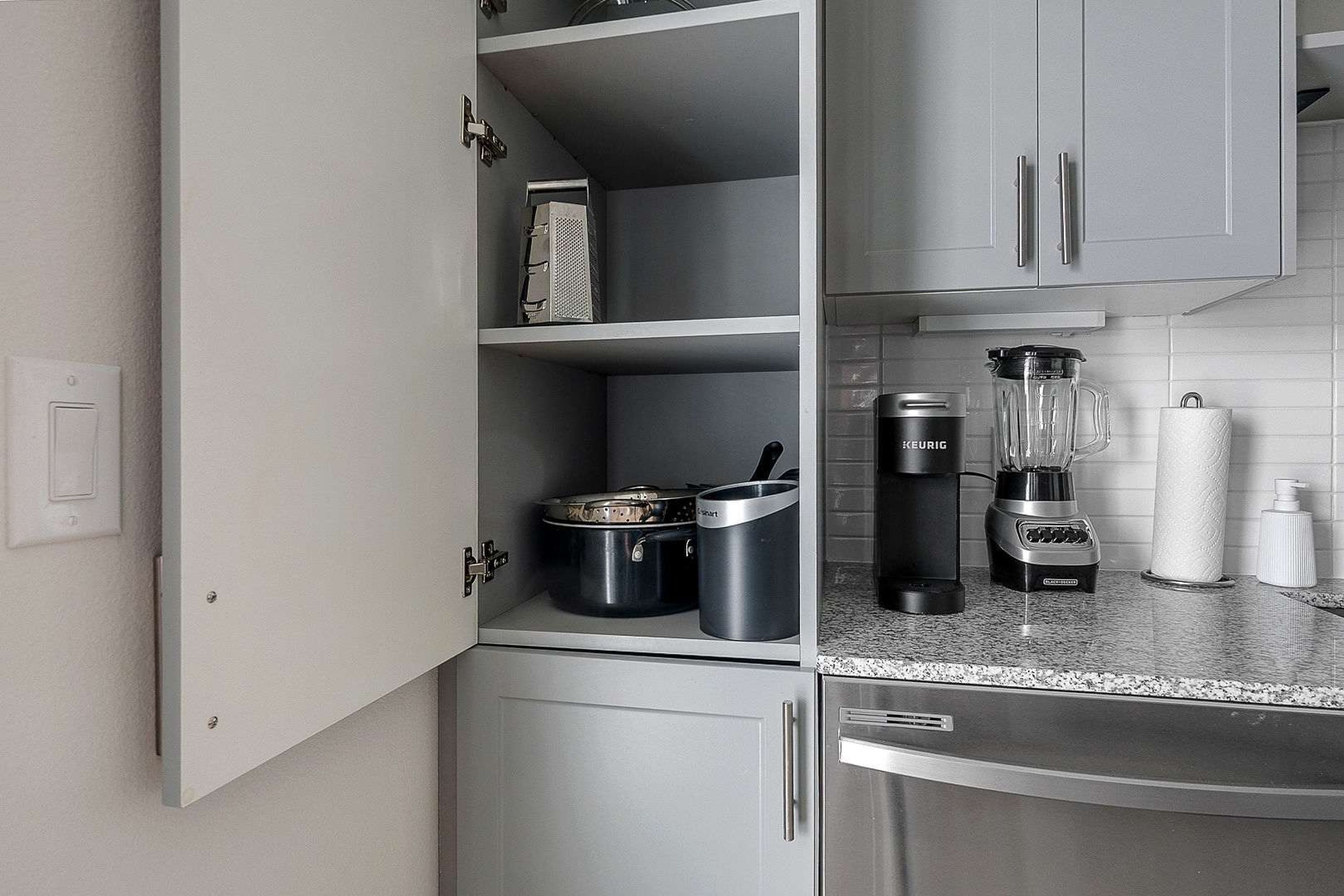 A kitchen with white cabinets, a coffee maker, a blender, and a kettle.