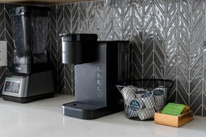 A kitchen with a coffee maker, a blender, and a basket of coffee pods. - Sapphire Shores Lakeside Escape Pet Friendly (Rowlett)