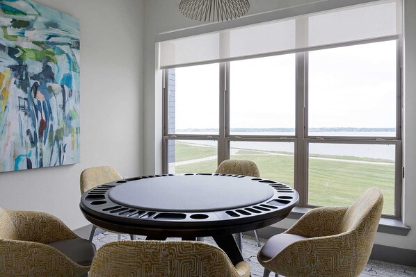 Una habitación con una mesa redonda, sillas estampadas, un cuadro abstracto grande y vistas amplias a través de ventanas.