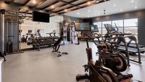 Un gimnasio con equipo cardiovascular, máquinas de pesas y una pantalla de televisión.