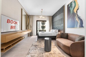 Ein modernes Hotelzimmer mit Bett, einer Couch, einem Fernseher, einem Gemälde und einem großen Fenster.