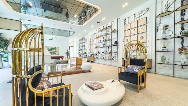 A spacious lobby with modern furnishings, a piano, and a large wall of decorative shelves. - Free Housekeeping Visits During Your Stay - Stayshort - Modern 1 Bedroom in Dubai Hills That Sleeps 4 Great Location (Dubai)
