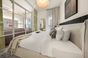 Ein modernes Hotelzimmer mit einem großen Bett, einem Spiegel, Blick auf die Stadt und einem Schild mit der Aufschrift 'DOCK ME'.