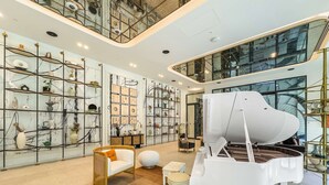A spacious living room with a grand piano, modern shelving with decorative items, and a high ceiling with skylights. - Free Housekeeping Visits During Your Stay - Stayshort - Modern 1 Bedroom in Dubai Hills That Sleeps 4 Great Location (Dubai)