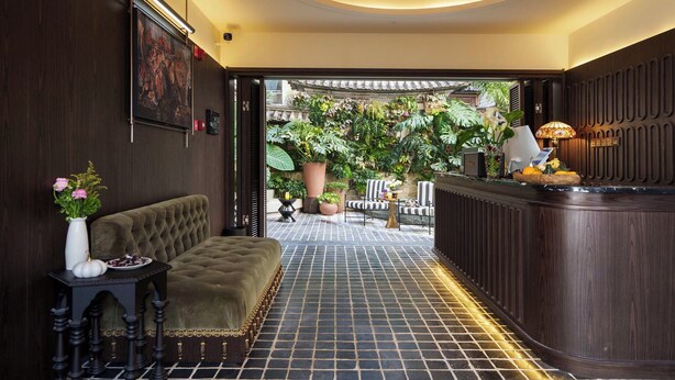 A lobby with a sofa, a reception desk, and a view of an outdoor garden. - BLOSSOM Floral Art Aesthetic Villa (Dali)