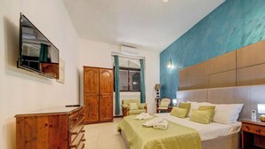 A bedroom with a bed, wooden dresser, and a mirror. - Gozo Couples Bungalow No 3 · Pool Use & Own Cabana (Gozo)