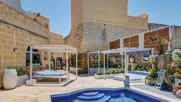 A pool area with a tiled swimming pool, sun loungers, and a covered seating area with a pergola. - Gozo Couples Bungalow No 3 · Pool Use & Own Cabana (Gozo)