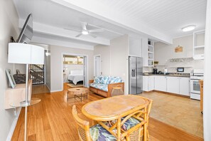 Eine moderne Küche mit weißen Schränken, einem Kühlschrank und einem Essbereich mit Tisch und Stühlen.