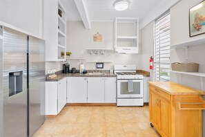 Eine moderne Küche mit weißen Schränken, einem Edelstahl-Kühlschrank, einem eingebauten Backofen und einer Holz Arbeitsplatte.