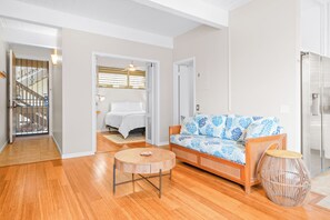 Ein modernes Wohnzimmer mit Holzboden, einem runden Couchtisch, einem gemusterten Sofa und einem Korbtisch.