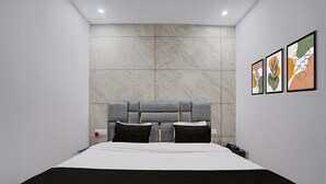 Un dormitorio moderno con una cama grande, una pared de mármol y tres obras de arte enmarcadas.
