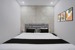 Une chambre à coucher moderne avec un grand lit, un mur en marbre et trois œuvres d’art encadrées.