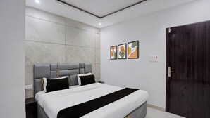 Un dormitorio moderno con una cama grande, una puerta de madera oscura y tres cuadros enmarcados en la pared.