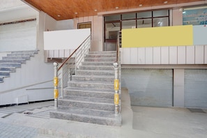 Un escalier avec des marches en marbre et des rampes en métal, menant à l’entrée d’un immeuble.